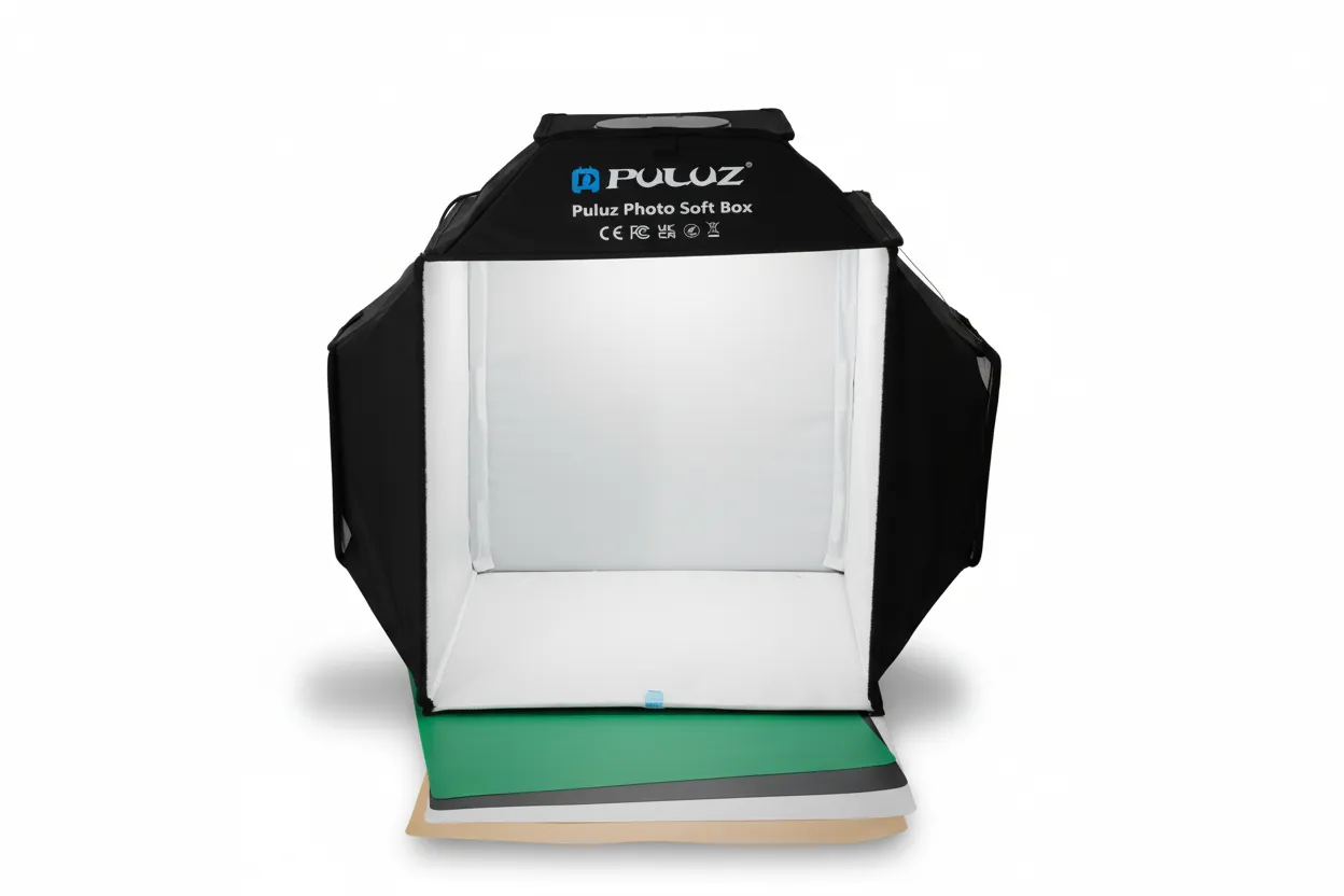 Caja de luz fotográfica plegable de 40 cm, equipada con sistema de iluminación de tres luces integradas. Incluye fondos intercambiables para distintos escenarios de fotografía. Diseñada para proporcionar iluminación uniforme en fotografía de producto. Funciona conectada a un tomacorriente mediante enchufe plano de 110 V. Fácil de montar, usar y almacenar.