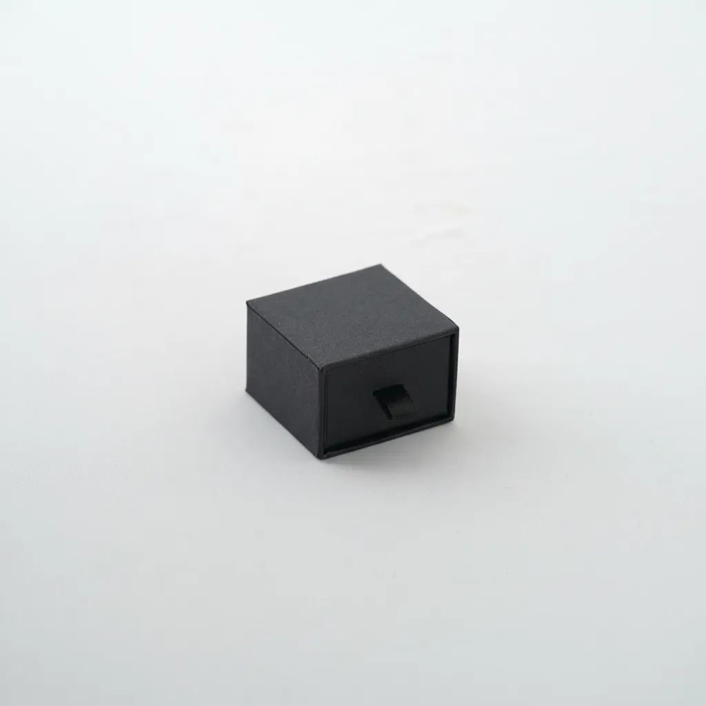 Caja de joyería para anillo y aretes de 5×5×3,5 cm, diseñada para la presentación y resguardo. Cuenta con soporte interior que permite colocar la pieza de forma estable y centrada. Fabricada en material rígido, ofrece protección durante la exhibición, entrega y almacenamiento. Su formato compacto proporciona una presentación limpia y ordenada, adecuada para uso comercial.