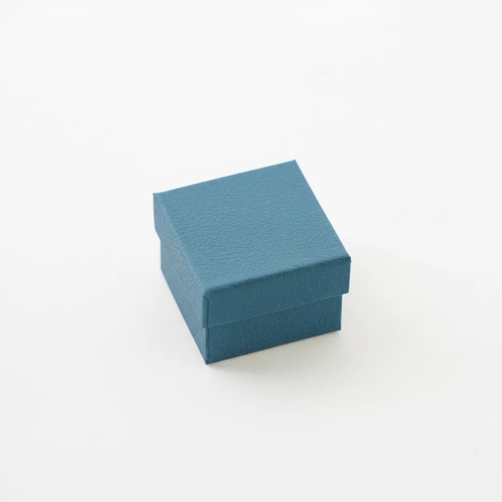 Caja de joyería para anillo y aretes de 5×5×3,5 cm, diseñada para la presentación y resguardo. Cuenta con soporte interior que permite colocar la pieza de forma estable y centrada. Fabricada en material rígido, ofrece protección durante la exhibición, entrega y almacenamiento. Su formato compacto proporciona una presentación limpia y ordenada, adecuada para uso comercial.