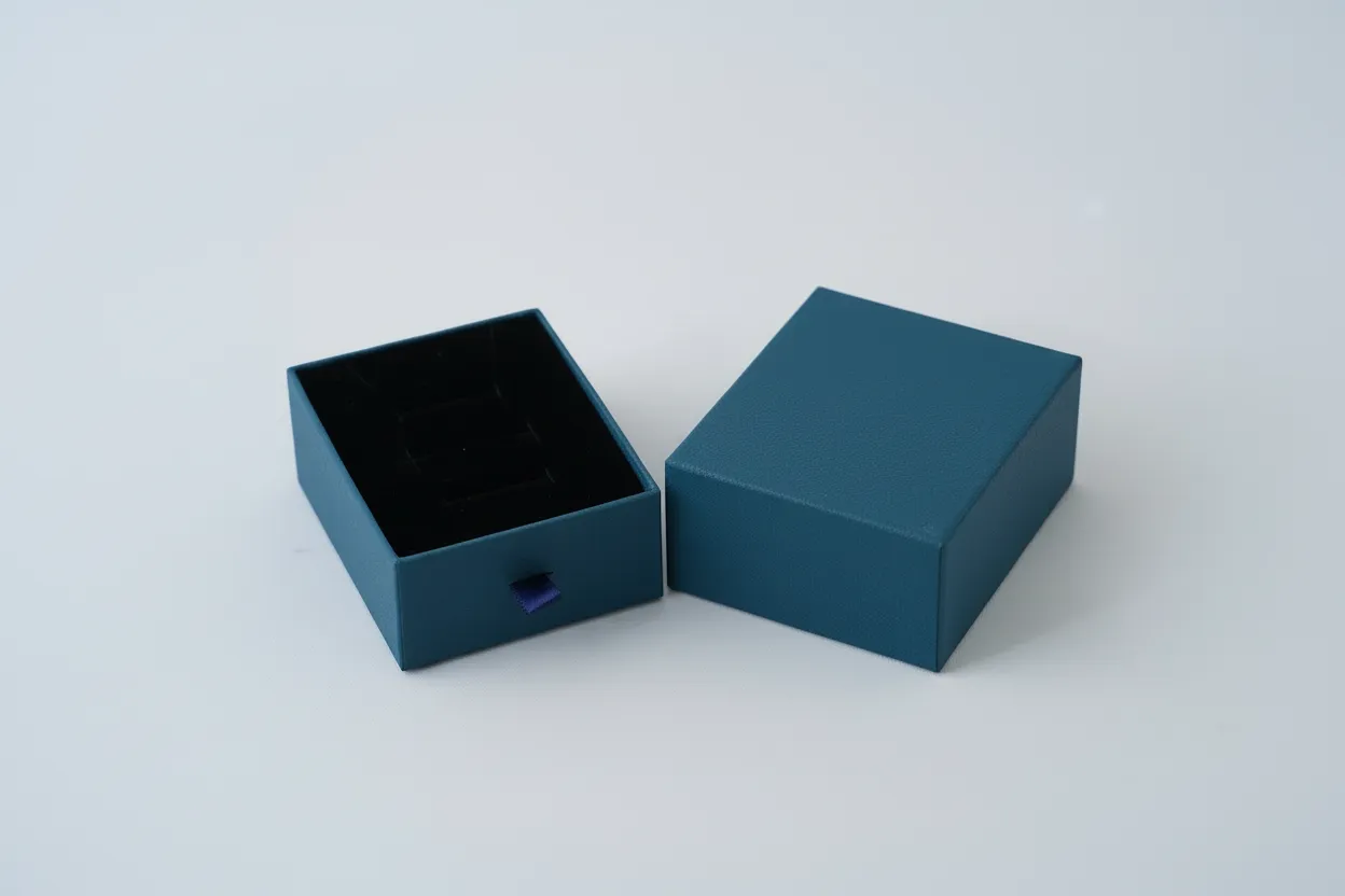 Caja cuadrada para joyería de 7×9×3,5 cm, diseñada para la presentación y resguardo de aretes grandes, dijes, anillos y sets pequeños de joyería. Fabricada en material rígido, ofrece una estructura resistente que protege las piezas durante la exhibición, entrega y almacenamiento. Su formato proporciona una presentación limpia y ordenada, adecuada para uso comercial.