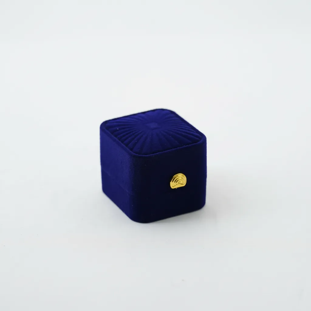 Caja de joyería compacta de 5,4×4,8×4 cm, diseñada para la presentación y resguardo de anillos y aretes. Cuenta con soporte interior que mantiene las piezas en posición estable. Su estructura rígida ofrece protección durante exhibición, almacenamiento y venta, brindando una presentación ordenada y profesional.