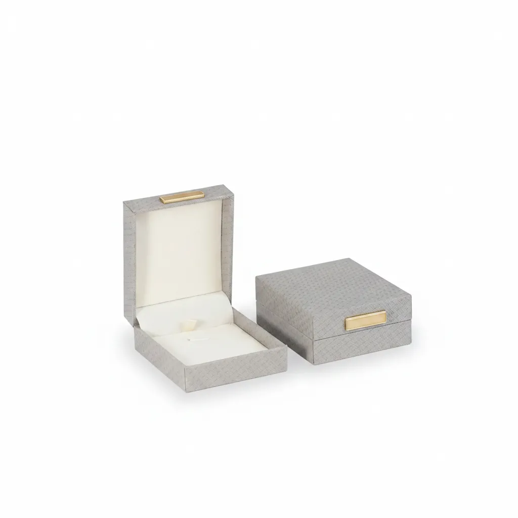 Empaque premium en tono gris de 7 × 8 × 3,5 cm, perfecto para presentar joyas con una imagen delicada, actual y de alta percepción.