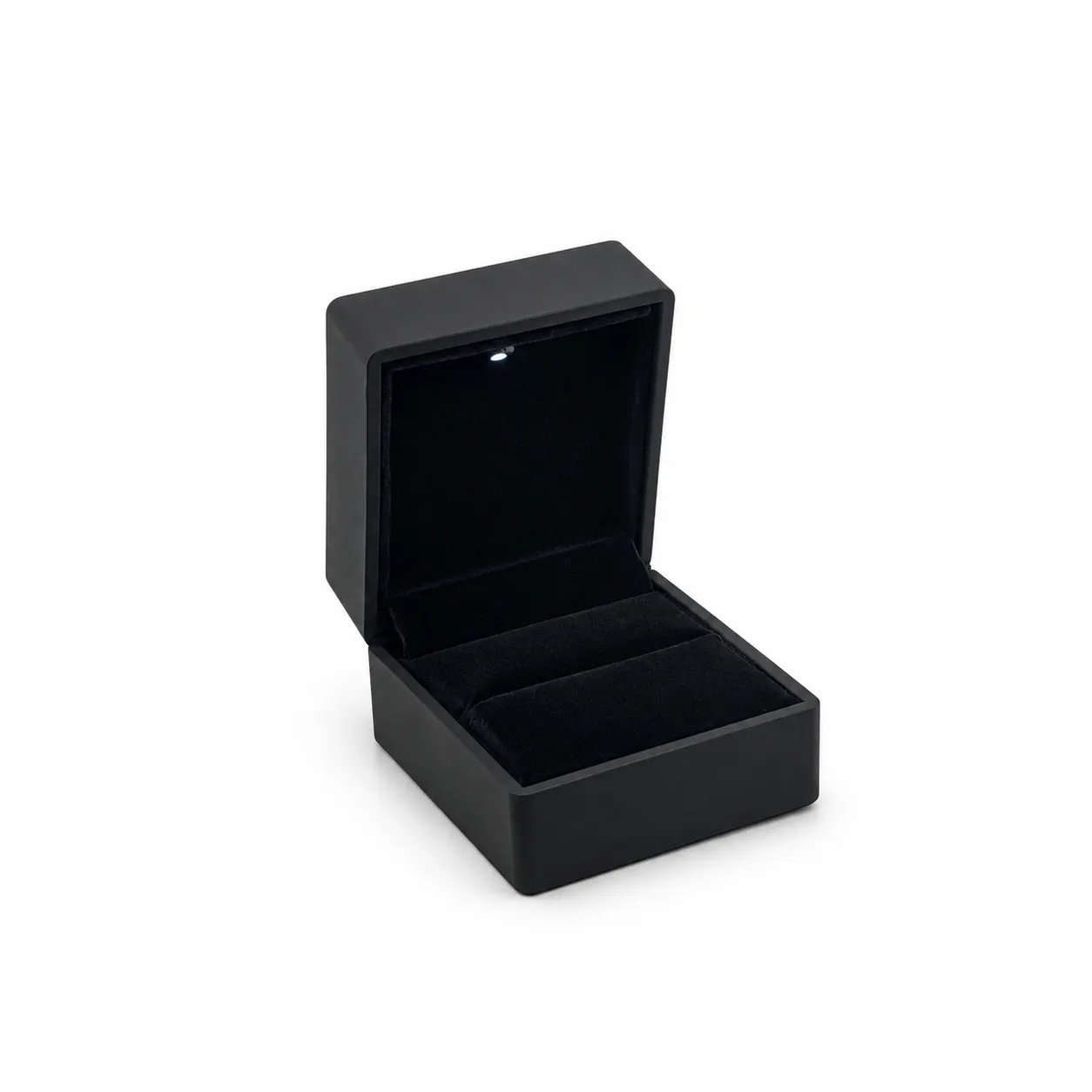 Empaque rígido compacto de 5,8 × 6,5 × 4,5 cm en color negro, con tapa abatible, interior acolchado y luz integrada. Ideal para resaltar anillos, aretes y piezas pequeñas desde el momento de la apertura.