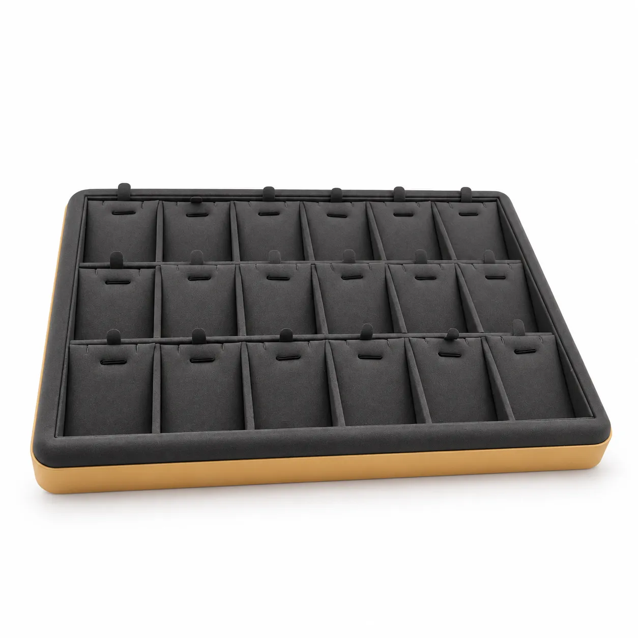 Exhibidor rectangular en color gris con 18 compartimentos acolchados individuales. Su distribución uniforme permite organizar y presentar anillos, aretes, dijes y otras piezas pequeñas con buena visibilidad y separación.